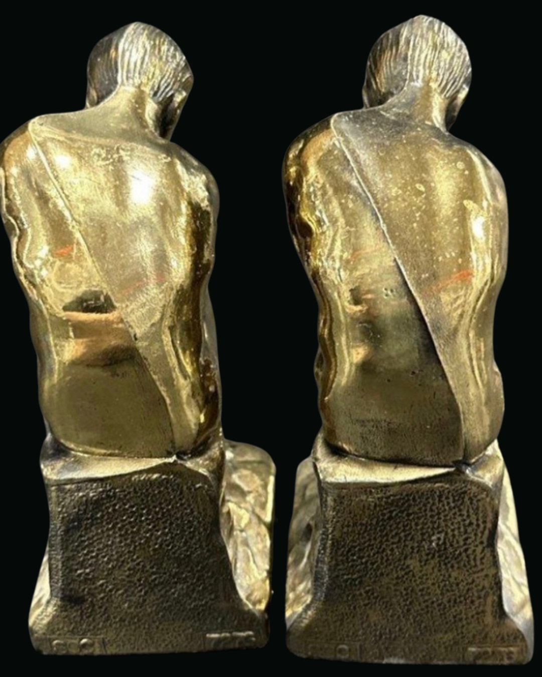 Back view of a pair of The Thinker bookends, brass finish worn bright across the shoulders, dark textured bases