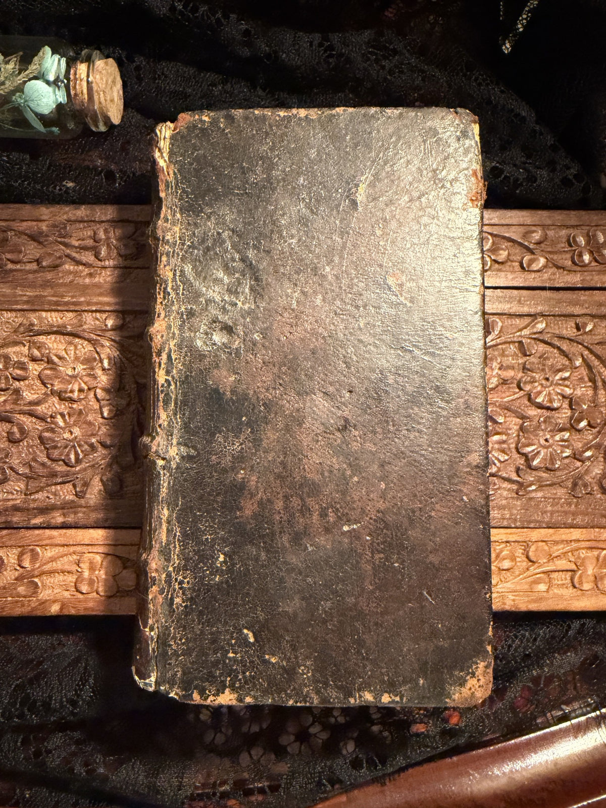 Worn dark leather front board of Les Confessions de S. Augustin on a carved wood panel, IM-0050