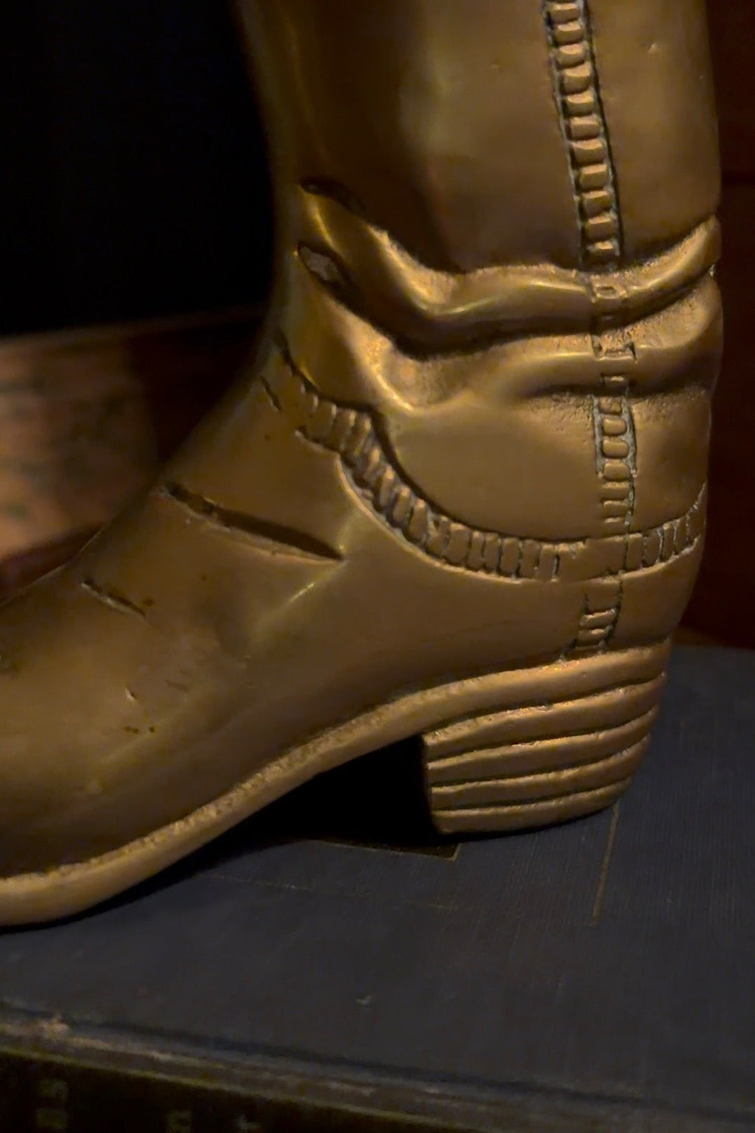 Close view of the brass boot's heel and tooled stitching detail