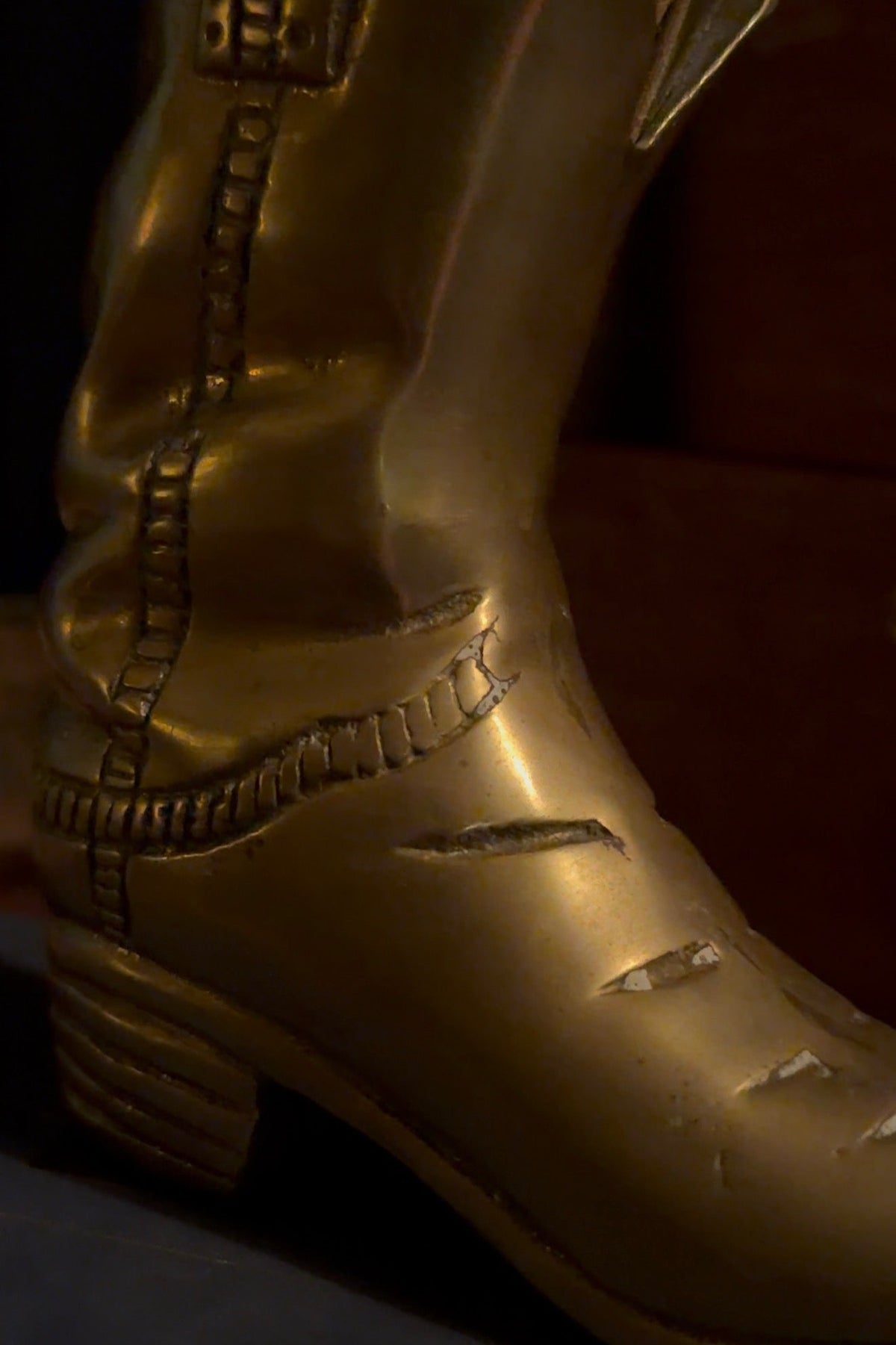 Close view of the brass boot's toe showing scratches in the lacquer